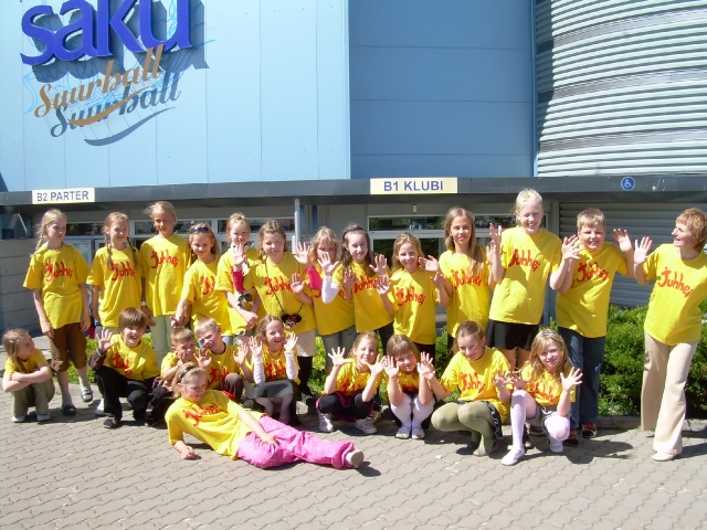 RÕÕM LOOTUSEST: Kambja mudilaslauljad ja koorijuht Marika Lehiste Juhhei koori päikesekollastes särkides heade elamuste maja – Saku suurhalli ees. Saku Originaal