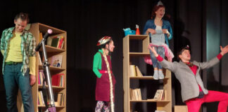 Tõrvandi raamatukogu pidas 75. sünnipäeva Etendus. Laval noormees teotumas raamaturiiulile, esiplaanil tõukeratas ja tööriistakohver. Keskel seismas maani ulatuva patsi ja rattakiivriga neiu. Tema kõrval seljaga pealambiga pintsakut kandev põlvele laskunud ja käsi taevasse tõstev noormees. Teisel raamaturiiulil istub diaaraga neiu tolmupühkimislapiga.