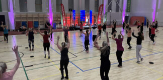 Rühmatreeningute päev Ülenurme spordihoones Treenijad saalis, treener laval, aktiivne tegevus, käes üles tõstetud.