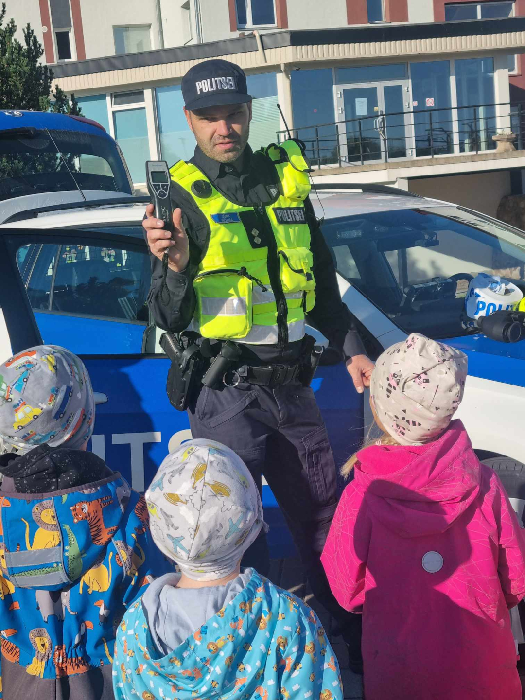 Politseinik lastele alkomeetrit tuvustamas.