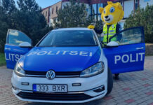 Lõvikostüümis politseinik politseiautoga.