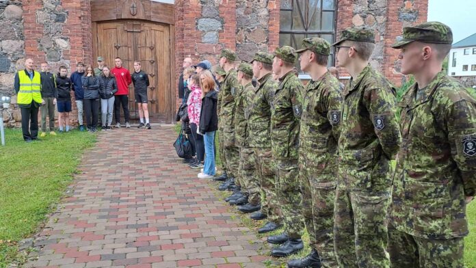 Jooksjad - õpilased ja sõdurid riivstunud kiriku külgkäigul.