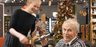 Koolmeistrina teada-tuntud Lembit Jakobson esitleb oma esimest luulekogu Pilt on tehtud raamatupoes, kus on hubane ja pidulik õhkkond. Taustal on jõulupuu kaunistustega, sealhulgas punased ja kuldsed pallid ning ehted. Lagi on kaunistatud paljude väikeste lampidega, mis loovad sooja valguse. Pildil on kaks inimest. Vasakul noorem naine, kellel on hele blondid juuksed, seotud hobusesabasse. Ta hoiab mikrofoni ja naeratab. Paremal istub vanem mees, kellel on seljas traditsioonilise mustriga villane kampsun. Mees hoiab käes ka mikrofoni ja tal on põlvedel pruun nahast portfell. Nad paistavad valmistuvat esituseks või aruteluks. Keskkond tundub pidulik ja seotud jõulude või talvehooaja sündmusega. Tagaplaanil on näha raamatuid ja riiuleid, mis viitab raamatupoe atmosfäärile.