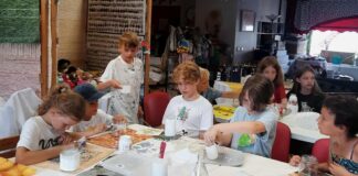 Toredad töötoad Ülenurmel Lapsed istuvad käsitöötoas ja kaunistavad klaaspurke küünlaümbristeks.