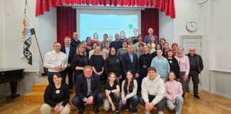 Vana-Kuuste mõisakoolis pandi alus uuele traditsioonile Koolisaalis tehtud grupifotol poseerib suur hulk eri vanuses inimesi – õpilased, õpetajad ja kogukonna liikmed. Esireas istuvad noored, nende taga seisavad täiskasvanud. Taustal on lava punaste kardinate ja projektoriekraaniga, millel on kiri „Kogukonnapäev Kuuste koolis“. Saali seinal on kell ning vasakul pool seisab lipp. Õhkkond on pigem sõbralik, viidates ühisele sündmusele ja kogukonna koostööle.